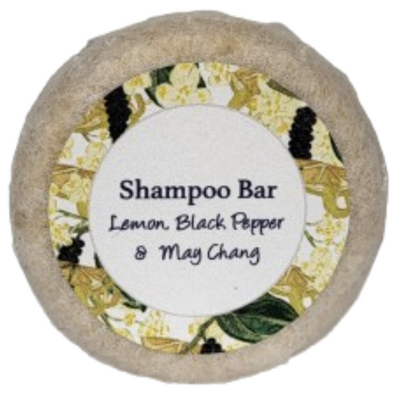 A round bar of lemon, black pepper and may chang shampoo on a blank background