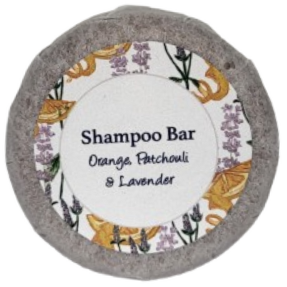 A round bar of orange, patchouli and lavender shampoo on a blank background